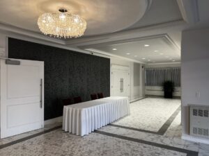 The lobby of the Polish Hall in Edmonton, AB, with marble flooring, chandelier, recessed lights, and a reception table.