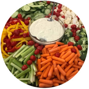 A vegetable platter containing carrots, celery, cucumbers, tomatoes, bell peppers, cauliflower, and broccoli.